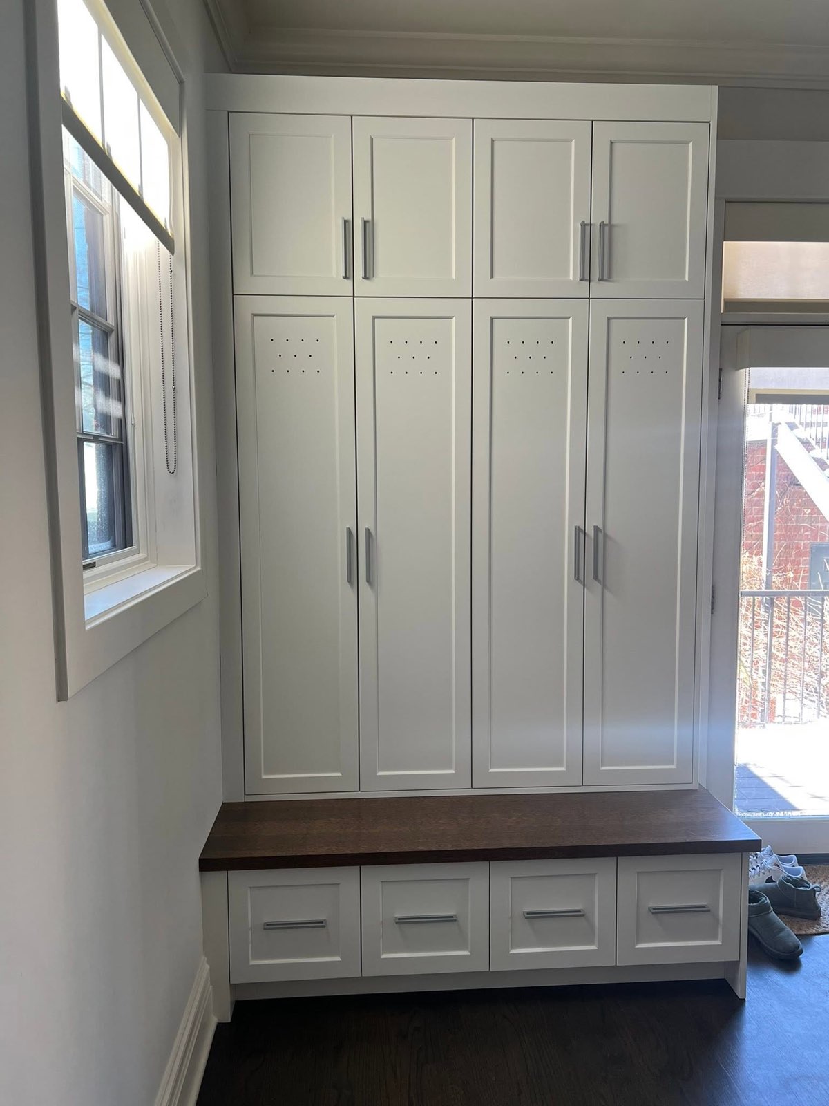 Custom mudroom locker wall with walnut bench and drawers